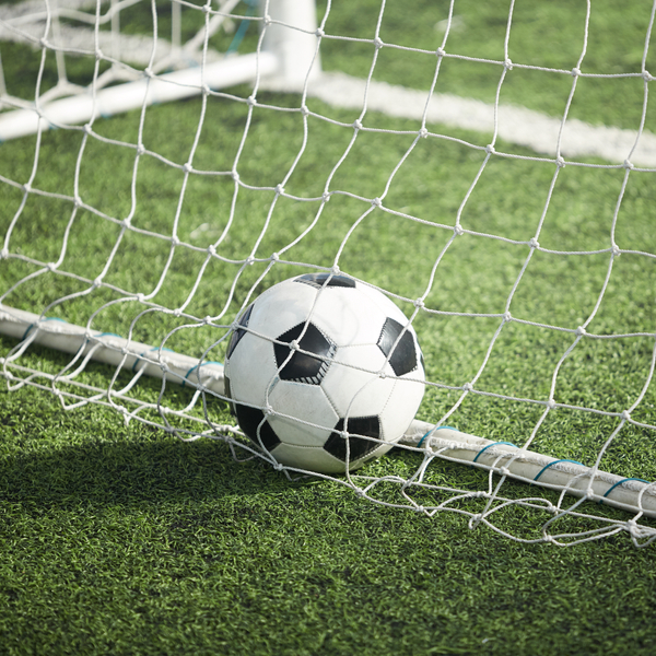 Medium angle of soccer ball in net on turf.